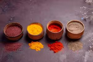 Glass jar filled with hot chili powder stored inside a dark kitchen cupboard beside a small metal measuring spoon