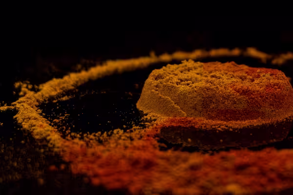 A sealed jar of chili powder placed in a cool dark storage area with a measuring spoon used for accurate cooking